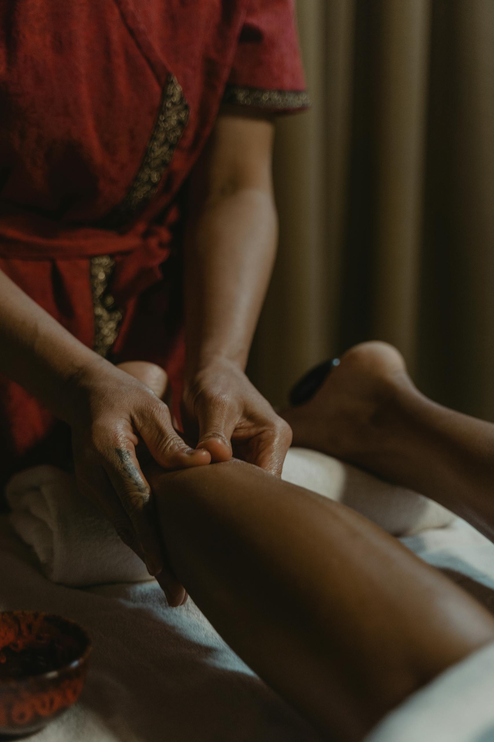 Close-up of hands giving a therapeutic leg massage at a spa, promoting relaxation and wellness.